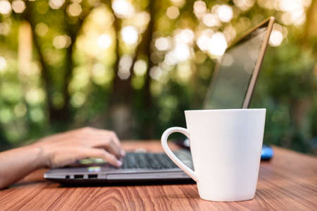 Fresh morning coffee while sitting by the laptop at the garden, Freelance is everywhere at work.の写真素材