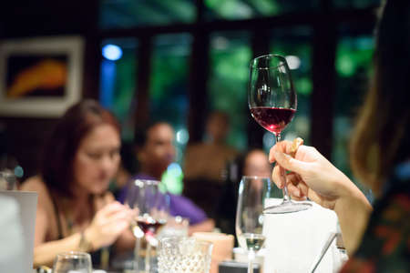 Woman holding a wine glass sipping a wine at a Thanksgiving party at a successful job.の写真素材