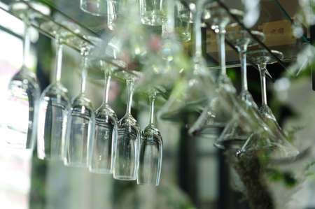 A glass of wine hanging on a bar of beverages.