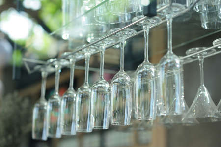 A glass of wine hanging on a bar of beverages.の写真素材