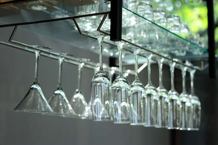 A glass of wine hanging on a bar of beverages.の写真素材