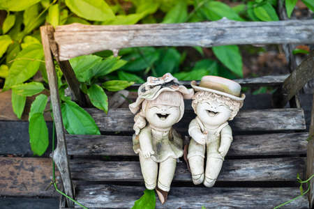 Two terracotta dolls sit and laugh in the garden. Represents the relaxation, happiness, peace and consciousnessの写真素材