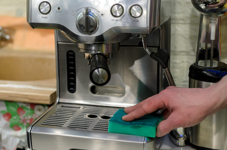Barista cleaning coffee machine at cafeの写真素材