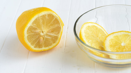 One cutted lemon and two slices of lemon into glass plate.の写真素材