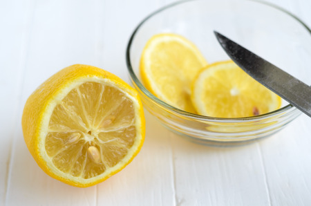 One cutted lemon and two slices of lemon into glass plate.の写真素材