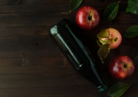 A bottle of a apple cider vinegar with three fresh apples and green leaves.の写真素材