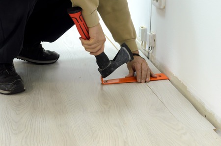 Renovation of an apartment, man laying laminate flooring in the room.