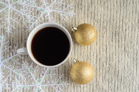 A Cup of coffee , decorated snowflakes and two pair Christmas golden ballson a light wool sweater.Winter concept.の写真素材