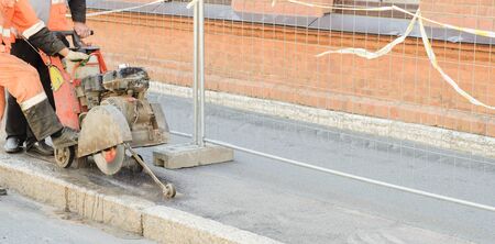 Road worker cutting asphalt road, working on the road reconstruction.Panorama view.の写真素材