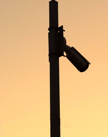 Silhouette of the Security camera on the pole on sunset..Space for text.Vertical view