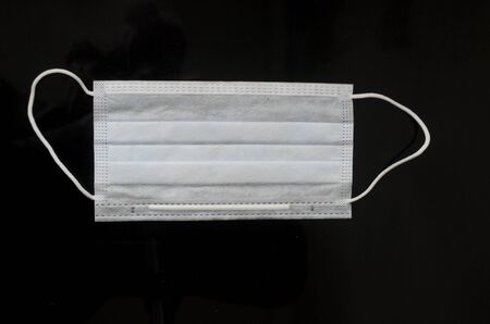 Coronavirus pandemic protection.Medical mask on black background.