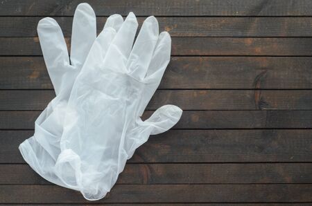 White disposable gloves on dark wooden background.Gloves for protection against coronavirus