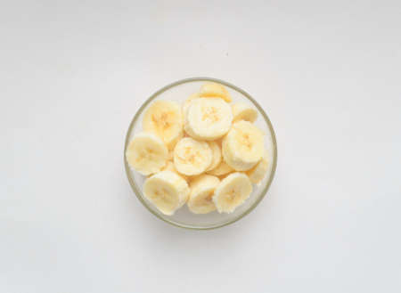 A peeled pieces of bananas in glass bowl on white backgroundの写真素材