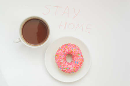 Top view,A cup of cacao drink and one glazed pink donut on white background.Sweet dessert.Stay home in warmの写真素材