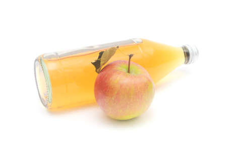 One whole apple with leaf and a lying bottle of apple cider vinegar isolated on white background.の写真素材
