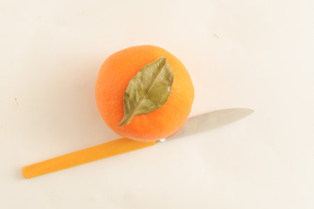 Top view, one whole mandarin with green leaf and a knife for cutting.の写真素材