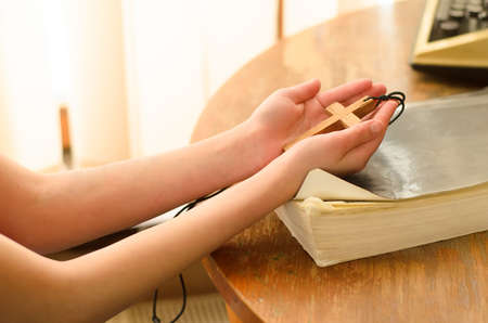 a teenage girl holds a christian cross in her hands.Concept of hope, faith, christianity, religion, church onlineの写真素材
