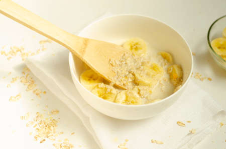 Oatmeal porridge with banana slices with a wooden spoon.の写真素材