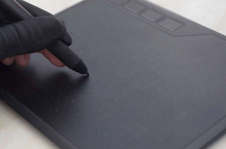 Graphic designers hand in a black glove draws on the workspace of a graphics table
