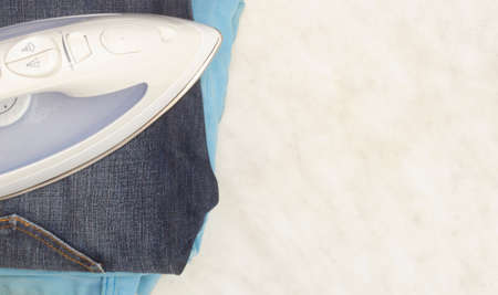 Steam iron, classic jeans and summer jeans on a light background, copy space.