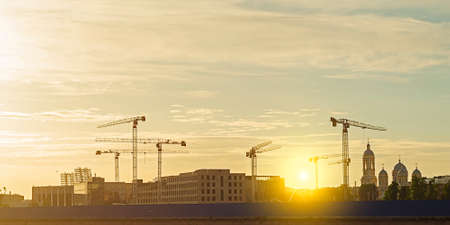 Construction cranes and buildings at sunset.の写真素材
