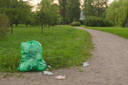 At sunset, a large bag of garbage and scattered garbage in the park.の写真素材