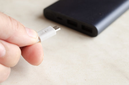 a man holds a charging cable for charging a powerbankの写真素材