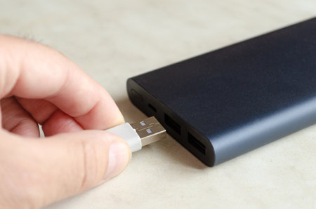man inserts usb cable into powerbank.Charging mobile gadgetの写真素材
