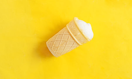 Vanilla ice-cream in a waffle cup on yellow backgroundの写真素材