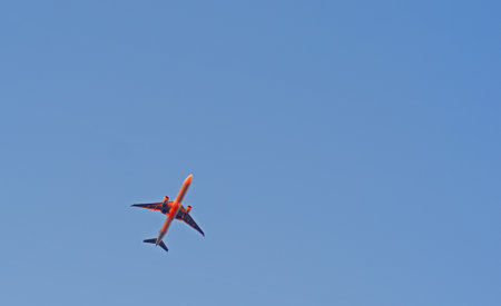 The passenger airplane is flying far away in blue skyの写真素材