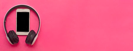 white wireless headphones and white smartphone on pink background.Listening of modern music in travelの写真素材