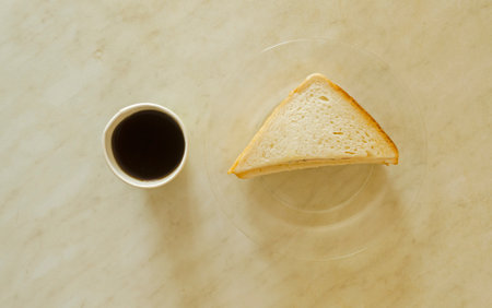A mug of black coffee and sandwich with ham on glass plate on table.Morning coffee.Fast snack