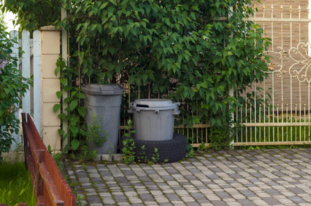 Two garbage bins at fence.Periodic garbage collection.の写真素材