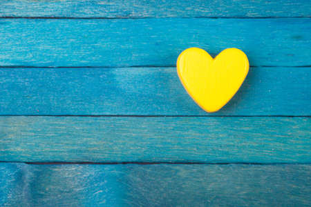 Decorative yellow heart on blue wooden backgroundの写真素材