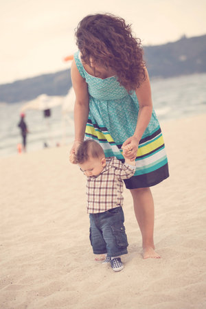 Mother Holding Baby for the First Step on the beachの写真素材