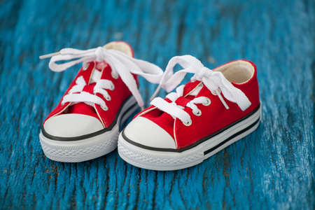 Red baby sneakers on wooden blue backgroundの写真素材