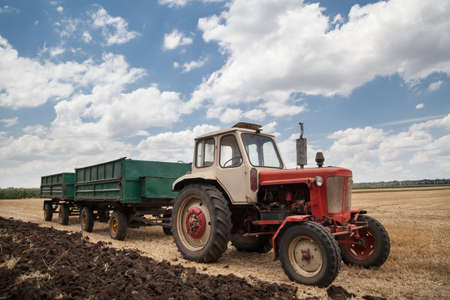 old tractor in field, against a cloudy skyの写真素材