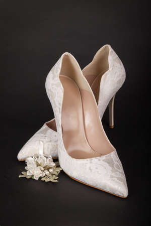 Elegant white female shoes on dark background. Bride shoesの写真素材