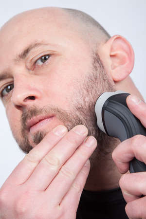 closeup of a man shaving his beard off with an electric shaver