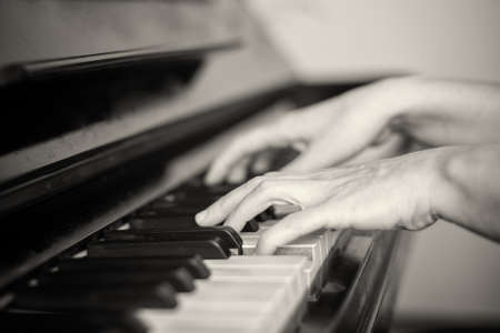 Close up of two hands playing piano, shallow focus. Black and whiteの写真素材