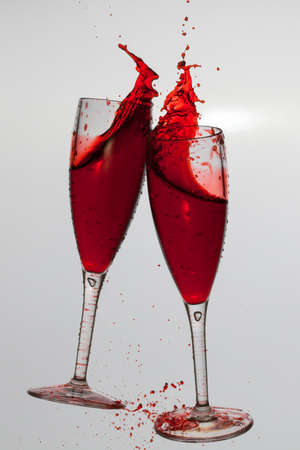 Two wine glasses in toasting gesture with big splashing.の写真素材