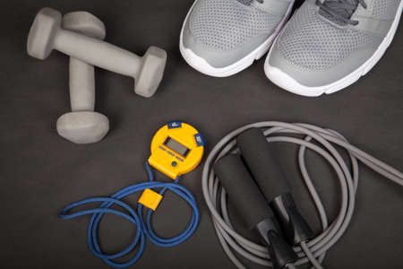 Sport shoes, dumbbells, skipping rope and digital stopwatch. Top view. Fitness, sport and healthy...