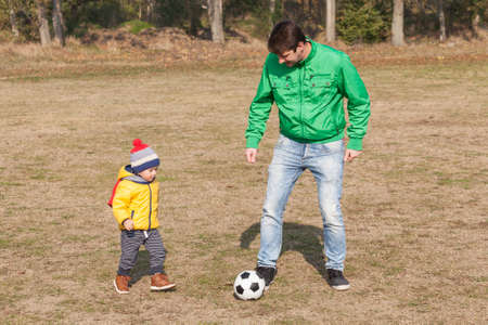 Young father with his little son playing football, soccer in the park