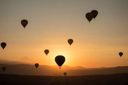 Hot air balloons in the sky during sunrise. Flying over the valley at Cappadocia, Anatolia, Turkey. Volcanic mountains in Goreme national park.の写真素材