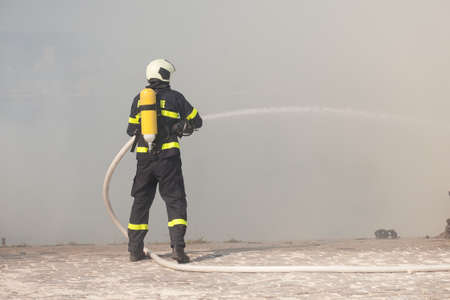 Firefighter in protective suit works with water hose. Fighting for a fire attackの写真素材