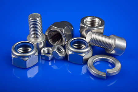 Bolts and nuts on blue background. Industry or construction concept