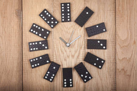 Vintage style clock made of domino plates on wooden background. Domino clockの写真素材