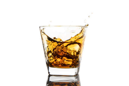Whiskey glass with ice splashes. Glass of splashing whiskey with ice isolated on white