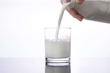 Pouring milk into a glass from bottle. white background