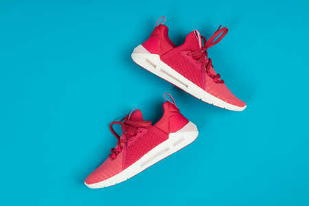 Pair of new pink sneakers, sport shoes on blue background. Pink womens sport, running shoes